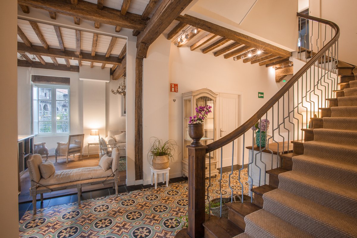 Hall de recepción con acceso la gran escalera de madera y vistas al salón