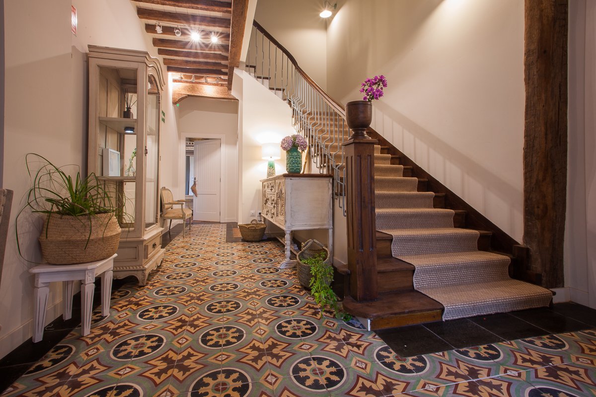 Hall de recepción de estilo rústico y gran escalera de madera original de la posada