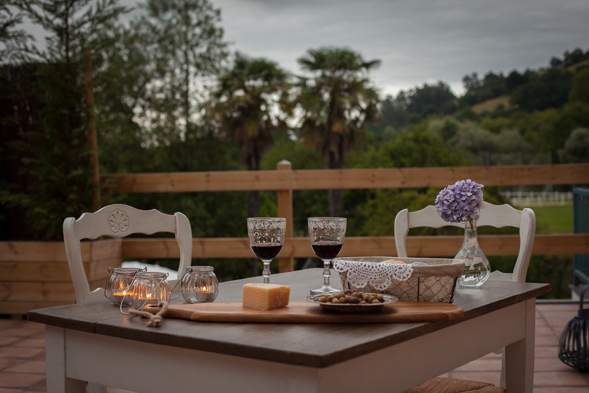 Vino y picoteo al atardecer en la terraza con vistas al jardín de la Posada